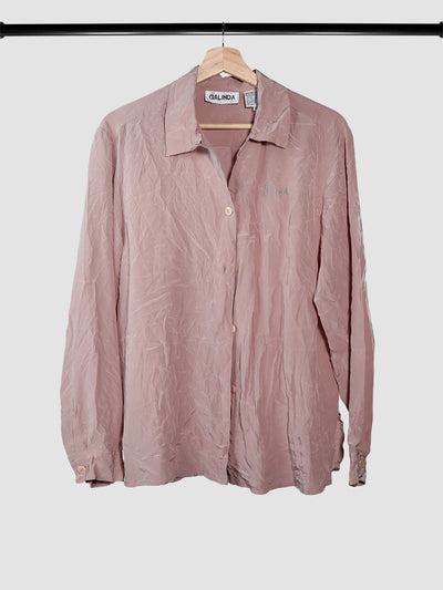 Pink silk button down shirt on a hanger