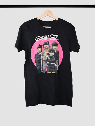 Gorillaz band characters on a pink circle background on a black t-shirt on hanger.